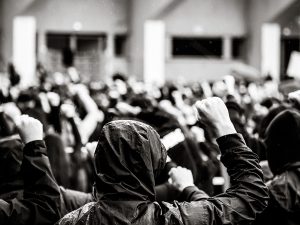 People wearing hoodies putting up their fists in protest. | Photo by Bayram Er/Pexels/MGBF File Photo